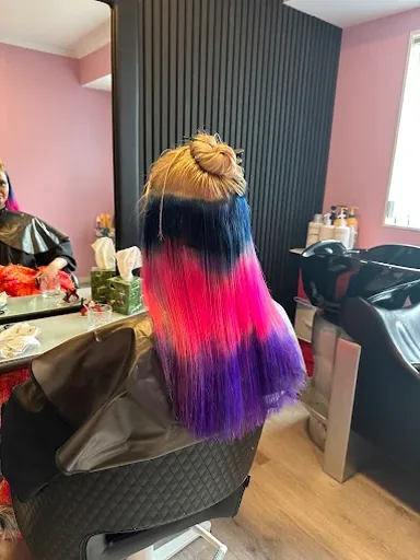 Long hair with a vivid colour melt from black to hot pink to purple, worn in a high bun