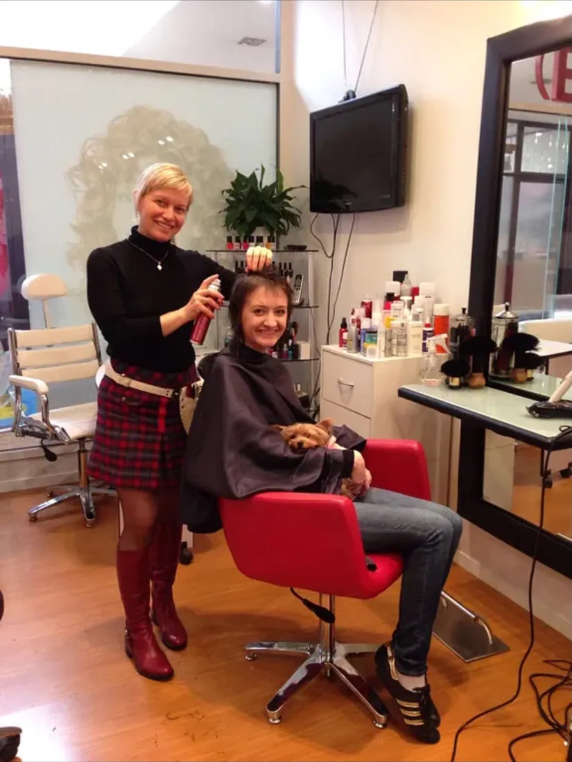 Yulia finishing a client's style at the Remuera salon, the client holding a small dog