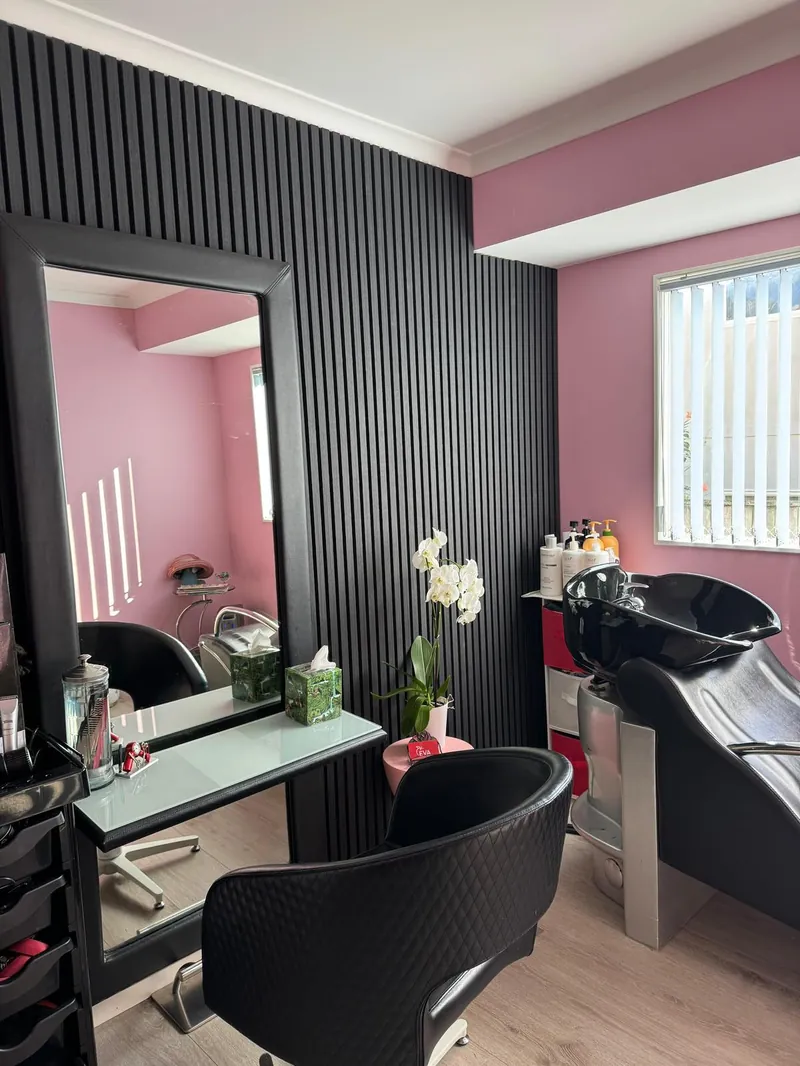 Eva Hair Salon interior with pink walls, black slatted panelling and a black basin chair